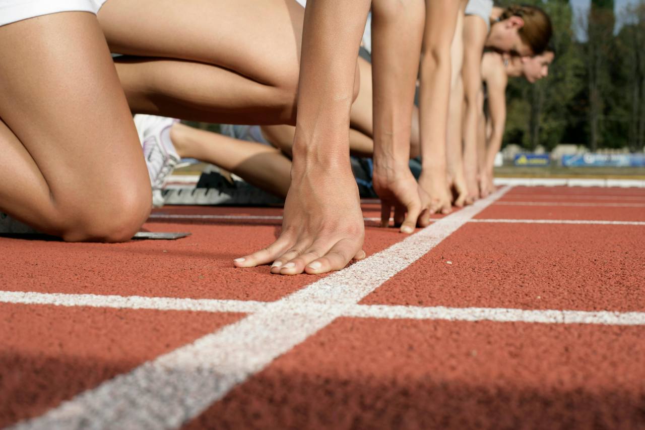 Atlete pronte alla partenza su pista di atletica durante allenamento di corsa femminile.